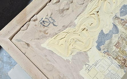 Detail of a carved panel in progress on a raw wood frame