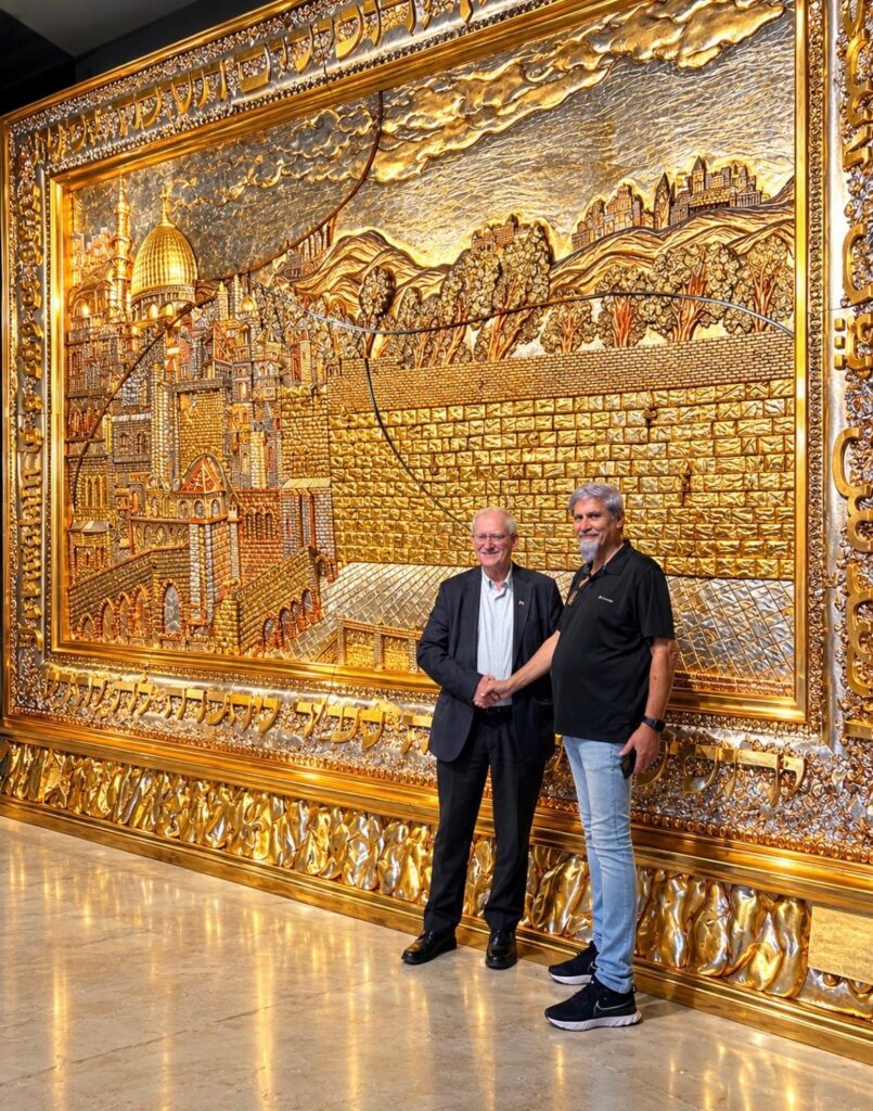 Visitor standing beside the gold relief of The New Jerusalem Monument